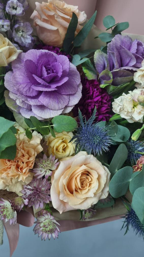 Ornamental kale with roses, sea holly, carnations, stock and astrantia
