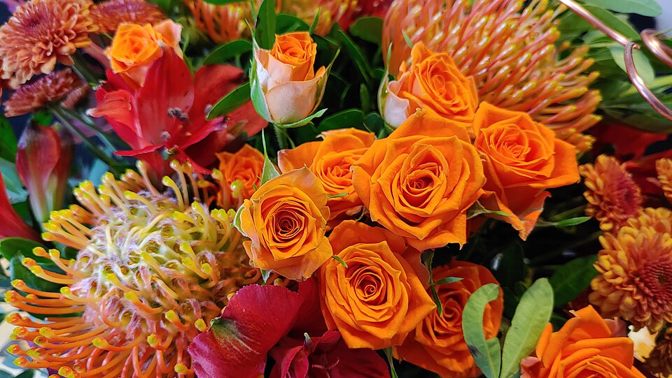 Protea and roses with orange zinnias