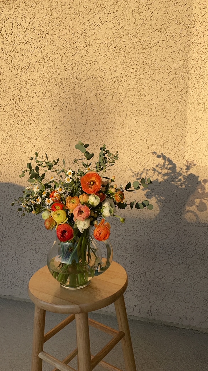 Ranunculus with eucalyptus in a vase; eucalyptus variety unspecified